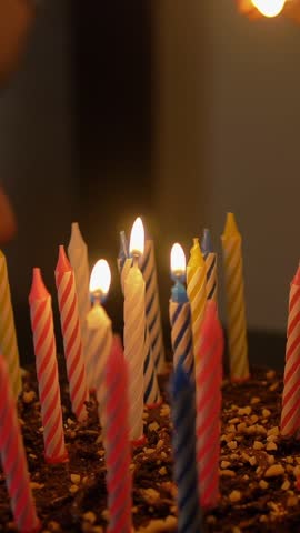 Male and female lights candles on tasty birthday cake. Prepearing for party. Only hands with Lucifer match. Vertical shot.