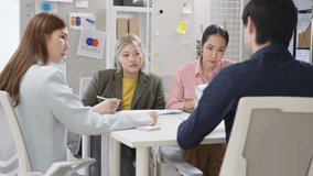 A focused team of Asian business professionals gathers around a conference table in a modern corporate office, deeply engaged in a financial consultation meeting. Surrounded by laptops, printed report - Powered by Shutterstock - Get 15% off with code: PIKWIZARD15