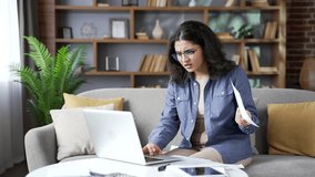 Confused young woman having difficulty doing household finances using application on laptop computer sitting on sofa in living room at home office. Puzzled shocked female looks at large utility bills - Powered by Shutterstock - Get 15% off with code: PIKWIZARD15