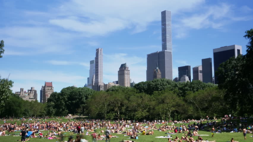 A timelapse view of activity on Sheep Meadow in Central Park during Gay Pride Month in midtown Manhattan. The iconic city skyline with upscape apartment buildings in the distance.  	