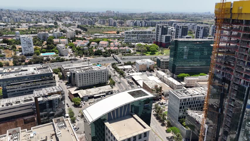 Aerial drone view of Herzliya, Israel, showcasing the city’s industrial and commercial district. Modern office buildings, tech companies, and urban layout near the Mediterranean coast.