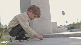 Young child drawing with chalk on pavement near concrete pillar - Powered by Shutterstock - Get 15% off with code: PIKWIZARD15