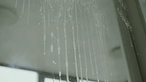 Low-angle view of white detergent dripping on glass window, creating vertical streaks and spots, preparing surface for cleaning and achieving spotless shine. Concept of household chores and hygiene. - Powered by Shutterstock - Get 15% off with code: PIKWIZARD15