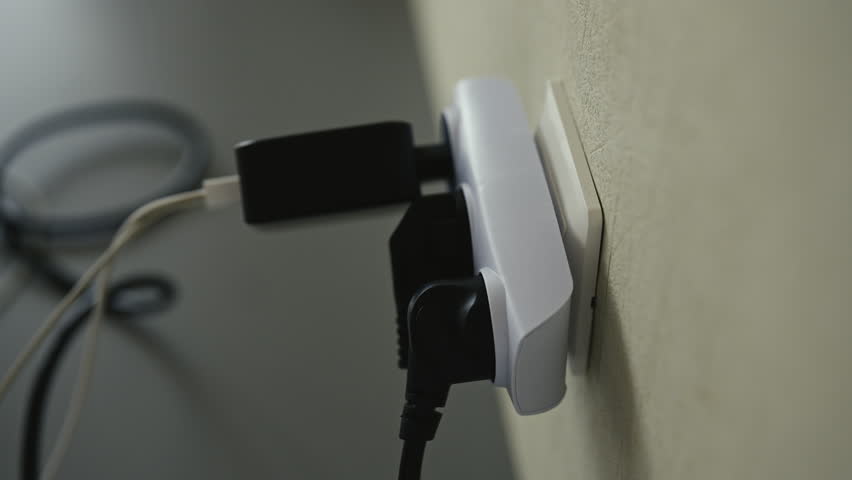 Close-up of man connecting power plug into white tee outlet connected to wall socket, with USB cable and adapter plugged in, illustrating electricity usage and device charging, close-up, slow motion.