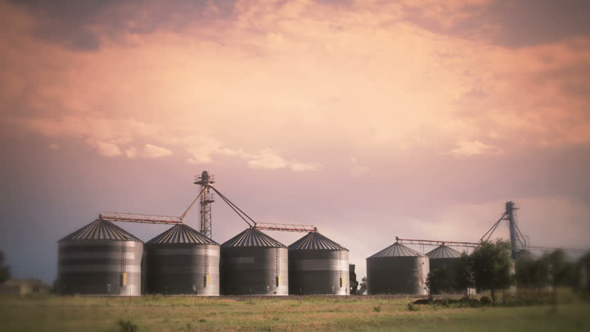 Stylized timelapse of a thunderstorm and clouds over silos in a rural setting.