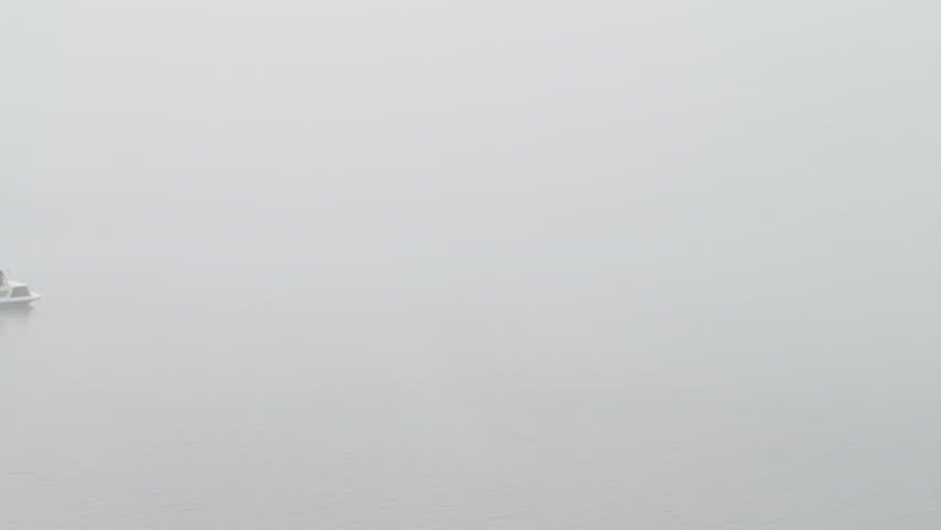 Small boat disappears into thick fog on a lake in Colorado. HD 1080p.