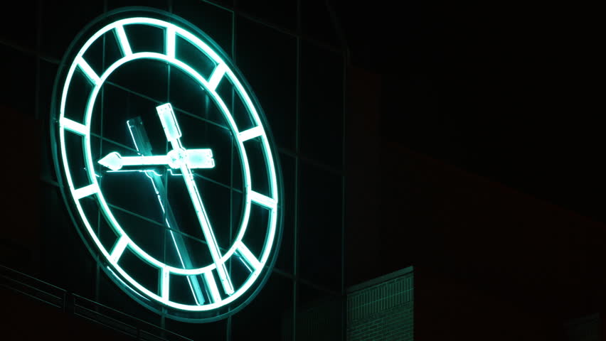 Huge neon clock on a building, at night. HD 1080p timelapse.