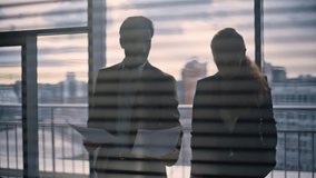 Businesspeople silhouettes flipping documents standing gloomy cityscape office closeup. Woman assistant elegant director reading contract. Businessman manager talking with colleague discussing work - Powered by Shutterstock - Get 15% off with code: PIKWIZARD15