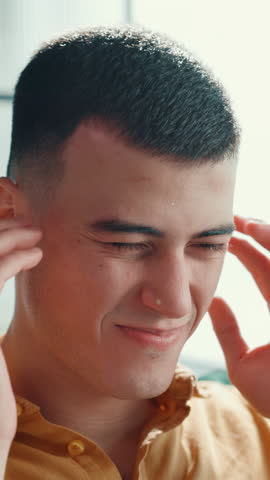 Frustrated man, headache and pain with stress for vertigo, dizziness or health emergency at home. Male person, ache or sore head with massage or migraine for muscle tension or eye strain at house