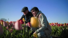 An elderly couple in a flower field enjoy the abundance of tulips before them - Powered by Shutterstock - Get 15% off with code: PIKWIZARD15