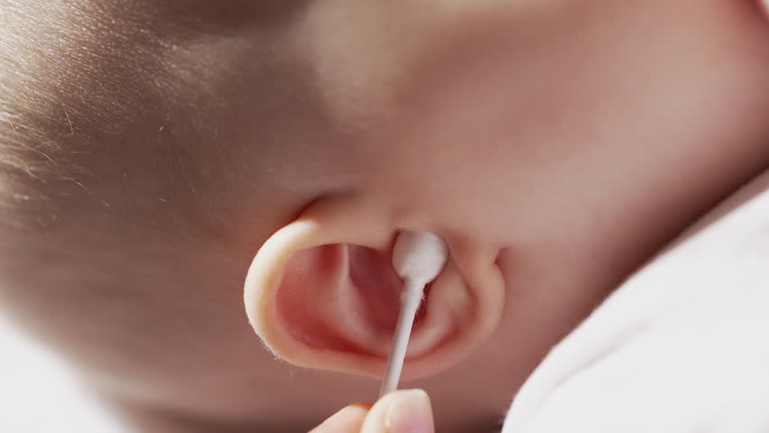 Mom cleans baby ear with cotton swab for infant. Newborn hygiene,morning routine