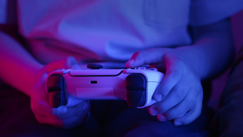 Gamer kid hands playing video game on console with Joystick.Schoolboy having fun