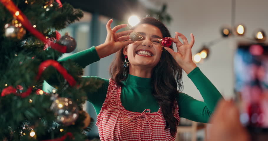 Picture, decorations and woman by christmas tree in home for playful memory or social media post. Goofy, photography and female person with baubles for camera at festive, celebration or xmas party.