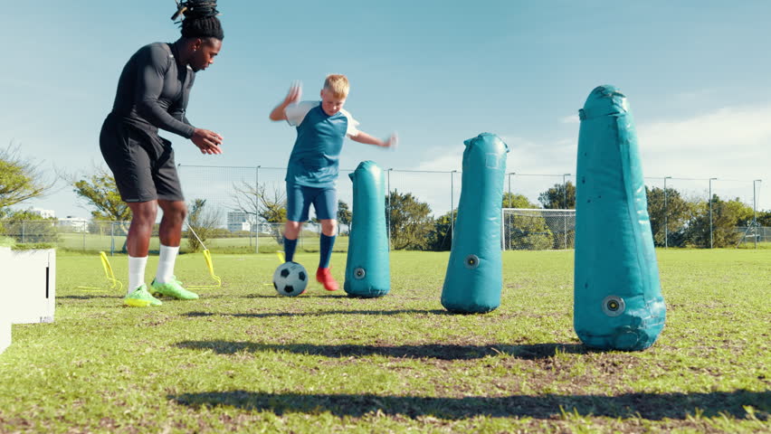 Dribble, practice or soccer with coach and kid on field for ball control, exercise or training. Children, drill and fitness with football player on sports pitch for agility, skill or technique