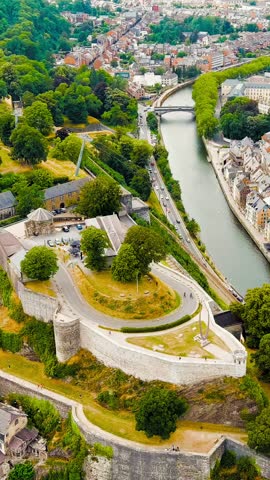 Vertical video. Namur, Belgium. Citadelle de Namur - 10th-century fortress with a park, rebuilt several times. Panorama of the central part of the city. River Meuse. Summer day, Aerial View, Departur