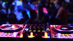 A DJ console that is vibrant and colorful, illuminated with vivid lights, at a lively party with a large dancing crowd - Powered by Shutterstock - Get 15% off with code: PIKWIZARD15