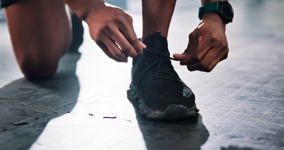 Person, hands and gym with tying laces for workout preparation, exercise or training on floor. Closeup, active or runner getting ready with shoe or tie for start, fitness or wellness at health club