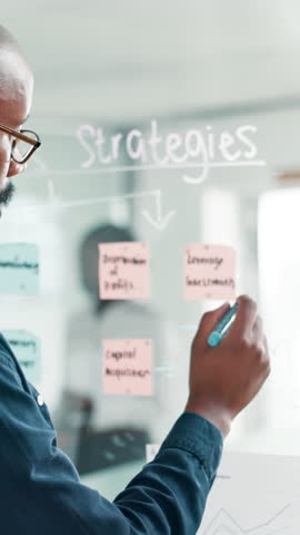 Office, businessman and writing on glass wall for brainstorming, planning and strategy for project. Workplace, male person and financial advisor with moodboard for investment solution, ideas or notes