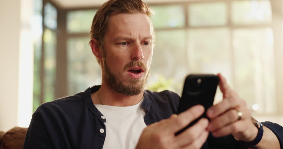 Man, phone and surprised with bad news in home with doubt, reading fake email or phishing scam. Sofa, person or shocked with smartphone for online announcement, internet glitch or mobile notification