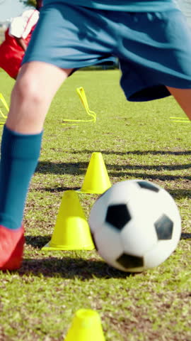 Legs, child and dribble with ball for soccer practice, kick training and fitness exercise. Kid, equipment and drill with cones for sports workout, skills technique and learning agility for team match