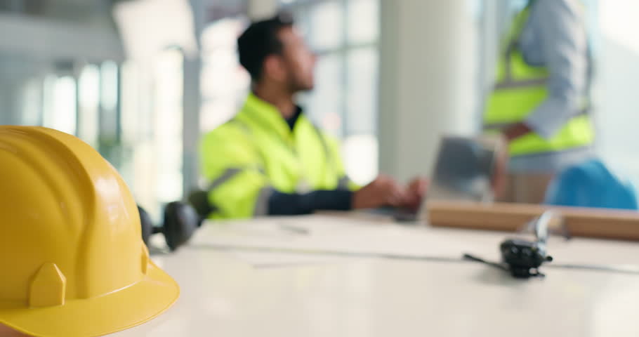Hardhat, blurred and construction workers in meeting on site for building, renovation or repairs. Safety gear, engineering and industrial employees with discussion on architectural planning in office
