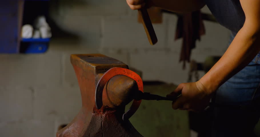 Male metalworker aligning glowing ring on anvil and hammering then rotating it for refining shape. Craftsman, workshop, industrial, craftsmanship, tools, manual, artisan