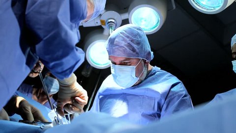Doctor wearing protective clothing performing surgery using sterilised equipment