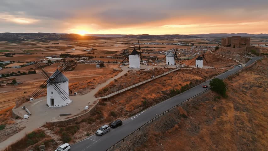 Aerial view of the historic windmills of Consuegra at sunset, Castilla-La Mancha, Spain. Old historic windmills of Don Quixote character on the hills in evening light. Molinos de Viento de Consuegra