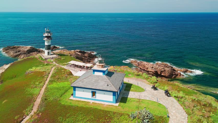 Aerial view of Faro de Ribadeo lighthouse in Lugo, Galicia, Spain. Scenic lighthouse on a rocky island on the Cantabrian Sea coast on a sunny summer day.