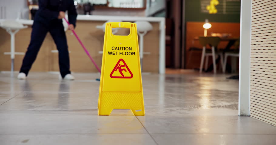 Janitor, person and office with wet floor sign, hygiene service and caution for disinfection. Attention, safety and warning for risk, cleaning and employee with tile polishing and maintenance worker