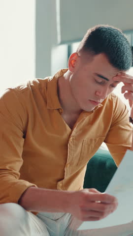 Stress, documents and worry with man on sofa for foreclosure, debt payment and bankruptcy. Insurance liability, bank loan rejection and account paperwork with person in home for eviction notice