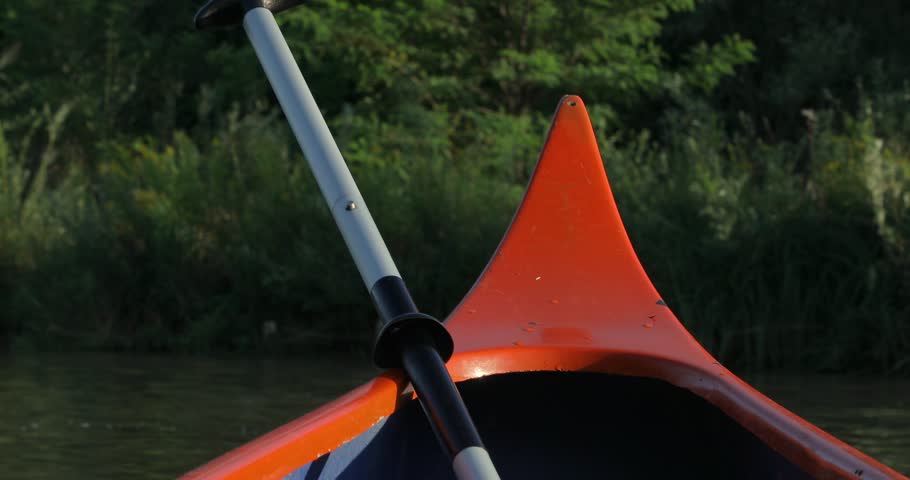 Canoeing in a beautiful natural environment, sunlight reflections, floating down with river current downstream, green vegatation, realxing mood