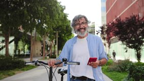 Senior man pushing bicycle using red cell phone app in the city. Portrait of healthy active person - Powered by Shutterstock - Get 15% off with code: PIKWIZARD15
