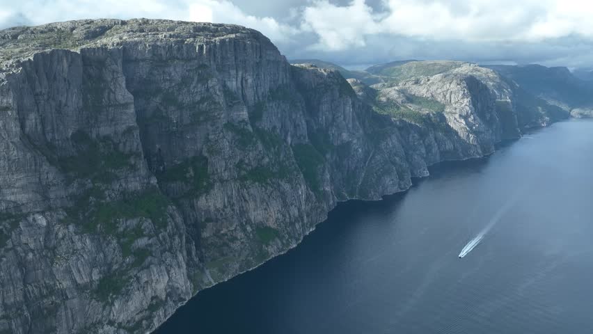 A drone shot of Lysefjord, Preikestolen (The Pulpit Rock), with a view of a motorboat in the water.