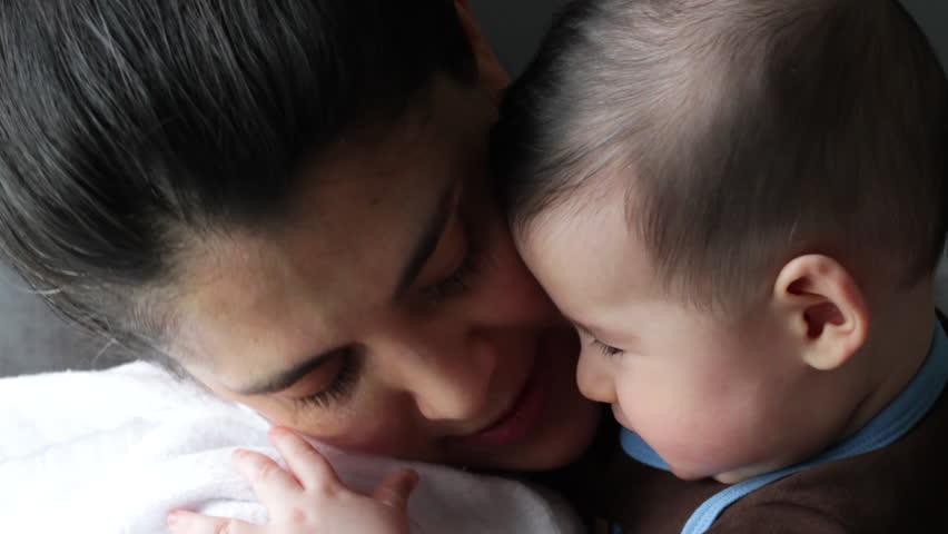 Baby boy (four months' old) touches mom's face while she holds him.