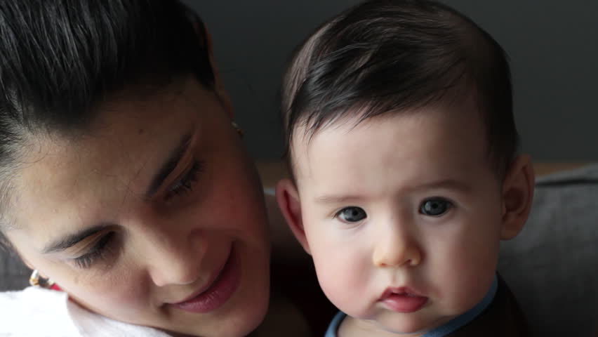Mother bounces her baby boy (four months' old) as he looks at the camera.