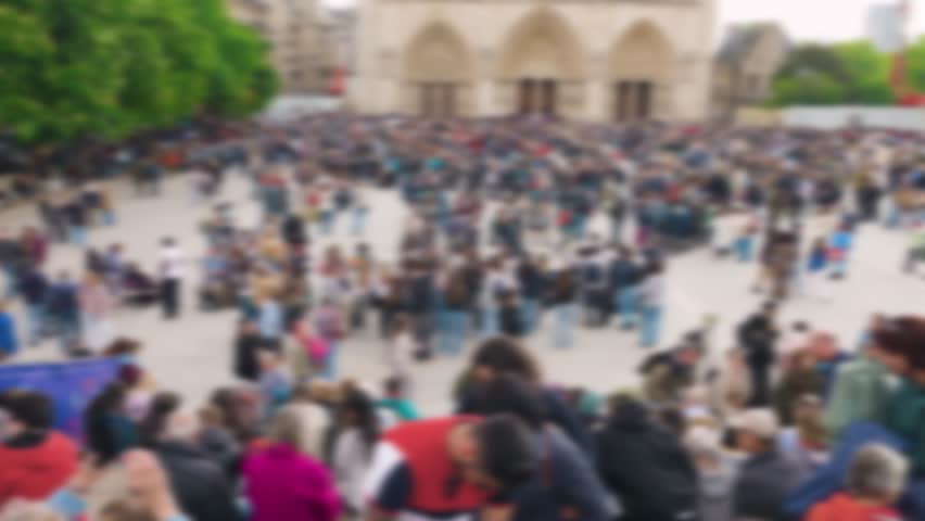Top view on crowd of tourists at the Place Jean-Paul II near the Catholic cathedral church Notre-Dame de Paris on the island Ile de la Cite, 4th arrondissement. Out of focus. Paris, France.