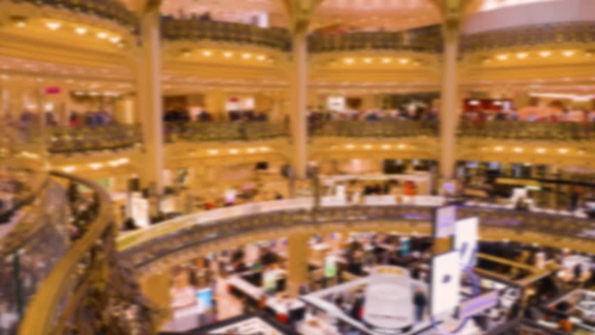 Inside view on Neo Byzantine dome, interio design in Art Deco style and visitors of upmarket French department store Galeries Lafayette Haussmann. Out of focus. Paris, France.
