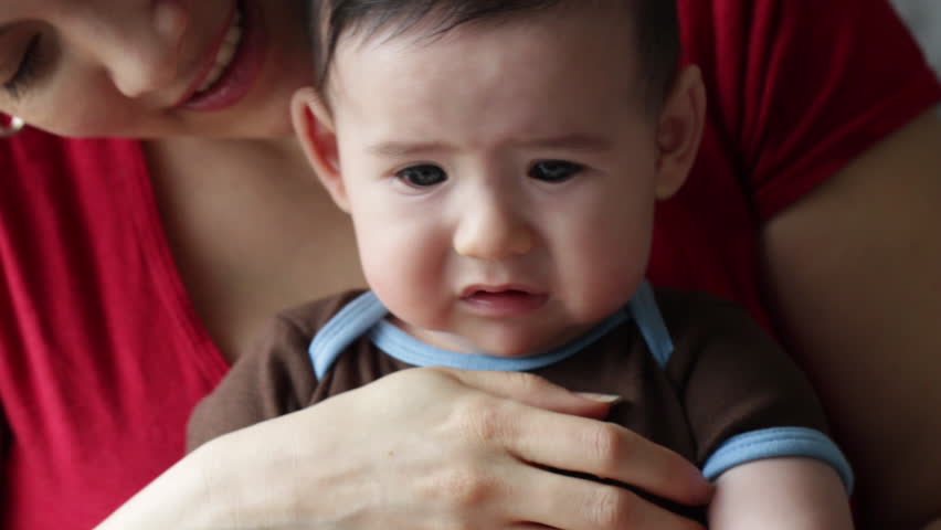 Unhappy baby boy (four months' old) about to burst into tears as he sits on
