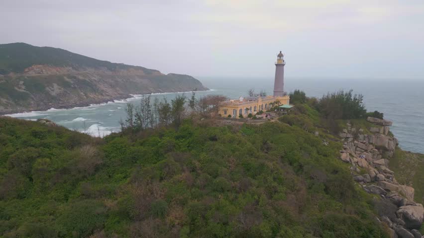 This location features a historic lighthouse standing tall on a rocky cliff overlooking turbulent waves. The surrounding landscape is lush and dramatic, capturing the beauty of the coastline at dusk.