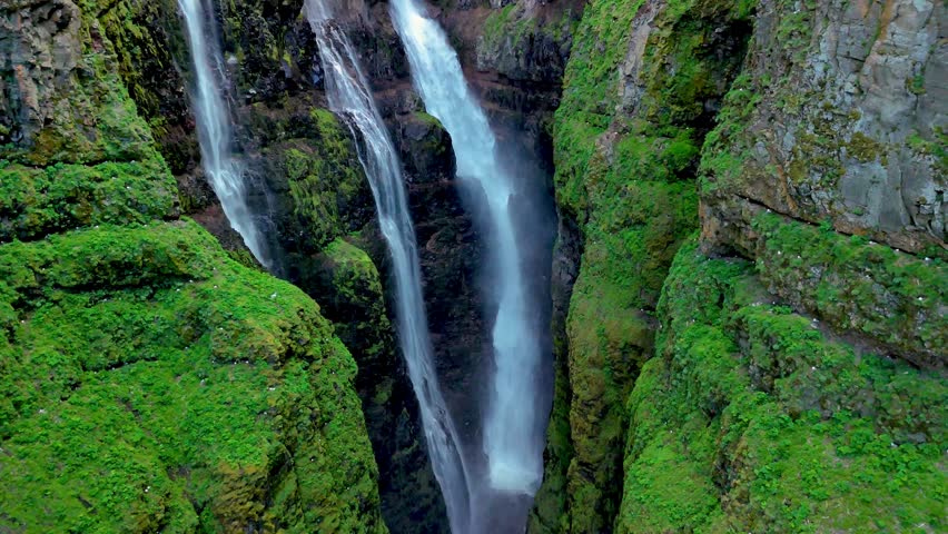 Witness the majestic beauty of dual waterfalls flowing gracefully between vibrant green cliffs in Iceland. Glymur waterfall canyon in Iceland