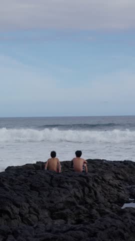 Two children are happily enjoying the breathtaking ocean view, captivated by surfers skillfully riding the waves. Slow motion