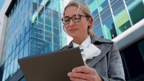 Professional woman engages with tablet outside modern office building during daylight - Powered by Shutterstock - Get 15% off with code: PIKWIZARD15