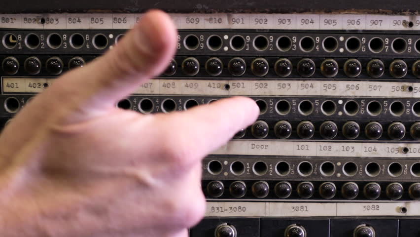 Hand points out details on an old telephone switchboard then plugs in cables.