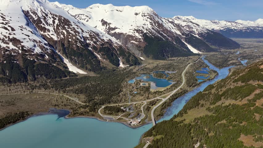 left panning 4k aerial video footage from area around "Begich, Boggs Visitor Center" across snow covered mountain range at Portage Glacier with Portage Lake until Anton Anderson Memorial Tunnel 