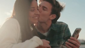 A young couple enjoys a beautiful sunny day in Seville, Spain, while looking at photos on their phone. They're happy and in love. - Powered by Shutterstock - Get 15% off with code: PIKWIZARD15