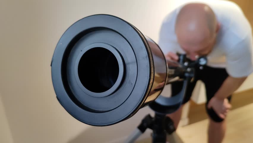 Man looks through telescope at night sky. Guy interested in science by studying stars. View from lens side. Home astronomy observatory. Close-up. High quality 4k footage