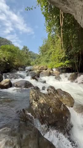 The clear river water flows rapidly behind the rocks, it is truly a beautiful sight