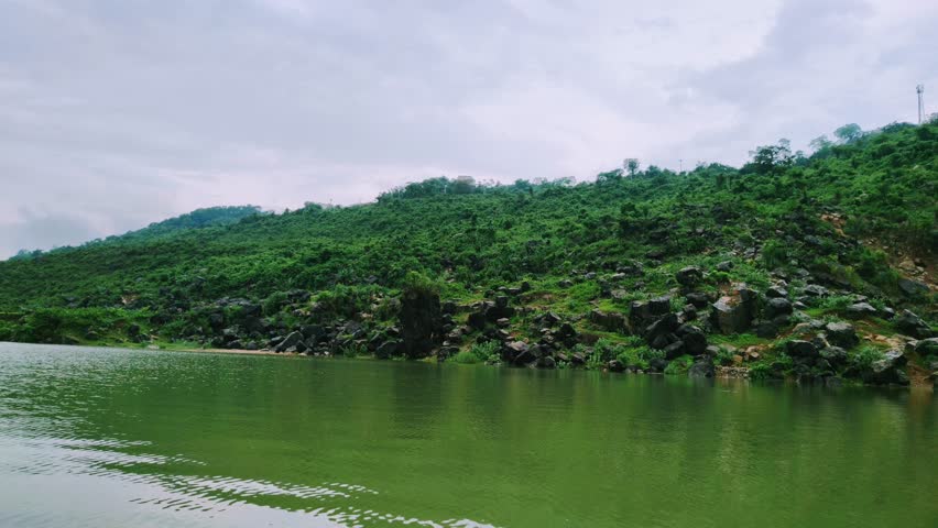 Tranquil boat ride on a calm lake with green hills and cloudy sky reflection perfect for nature exploration and outdoor adventure background.