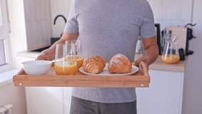 Close-up of a man holding a tray with breakfast with croissants and orange juice for himself and his wife. Breakfast in bed - Powered by Shutterstock - Get 15% off with code: PIKWIZARD15